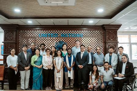 Group photo of diverse individuals posing together in a United Nations office setting.