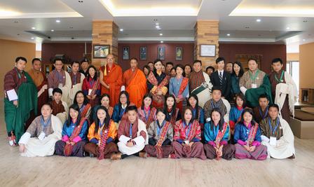 A large group of individuals in traditional attire poses together in a spacious indoor setting.