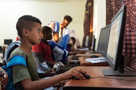 Children using computers in a classroom, focused on their screens.