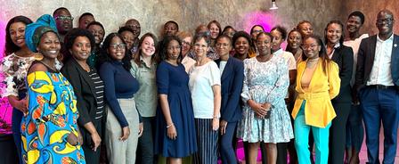 A diverse group of individuals smiling together in a brightly lit setting.