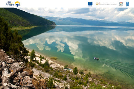Serene lake reflecting clouds and mountains, with a small boat on the water's surface.
