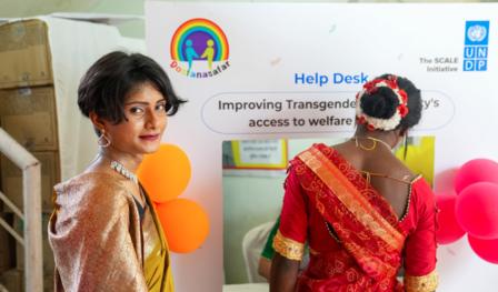 A person with short dark hair looks back while another person in traditional attire stands nearby.