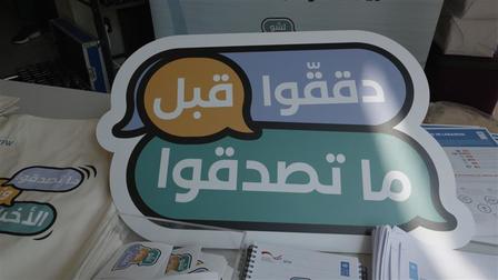 Colorful sign on a table with Arabic text in speech bubbles.