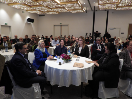 A diverse group of people seated at round tables in a conference setting.