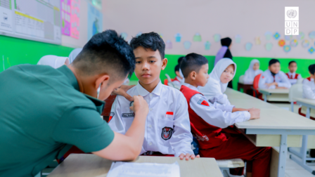 A healthcare worker administers a vaccine to a young boy in a classroom setting.