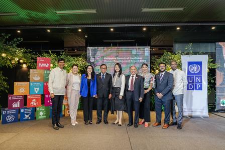A diverse group of people poses together at a sustainable event with vibrant backdrops.