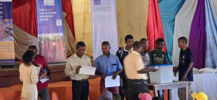 Group of young people participating in a voting event in a colorful hall.