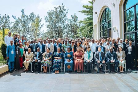 Group photo of diverse individuals posing outdoors in front of a large building.