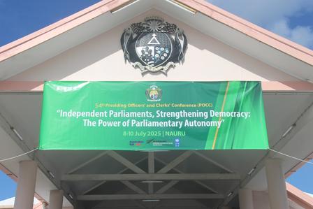 Green banner displaying text about parliamentary democracy, with a coat of arms above it.
