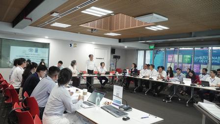 A meeting in a modern conference room with participants seated around a long table.