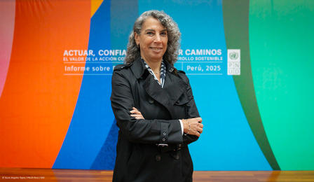 Woman in a black coat stands confidently with arms crossed against a colorful backdrop.