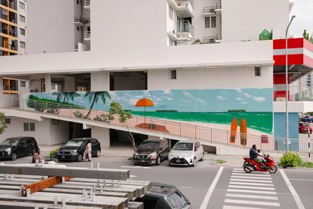 A colorful mural depicting a beach scene on a building, with cars parked below.