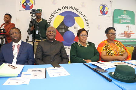 Four individuals seated at a table during a conference, with a backdrop displaying a logo.