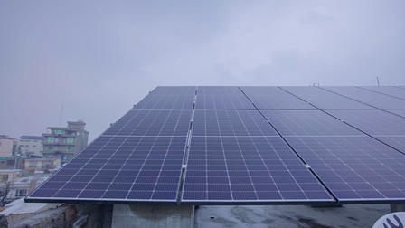Solar panels installed on a rooftop under a cloudy sky.