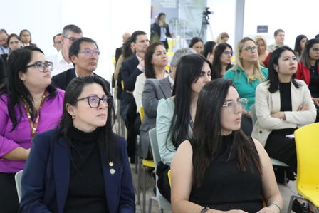 A diverse group of people seated in an audience, attentively listening to a presentation.