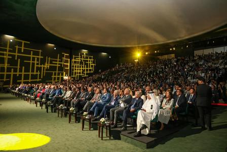 A large audience seated in a modern venue, with soft lighting and a stylish backdrop.