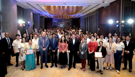 A large group of people stands together in a banquet hall, smiling and posing for a photo.