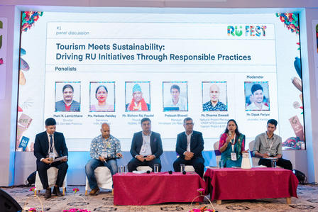 Panel discussion on tourism sustainability with six speakers seated at a long table.