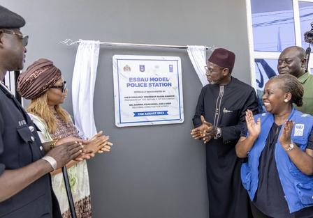 Group of officials celebrating the unveiling of a new police station sign.