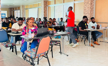 A group of students engaged in a classroom setting, with a speaker in a red shirt.