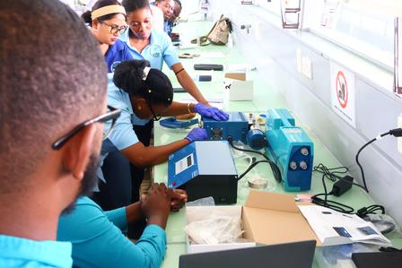 Group of people in blue shirts working with laboratory equipment at a table.