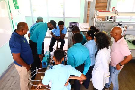 A group of students and instructors gather around a science project in a classroom.