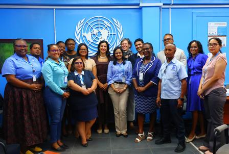 Group photo of diverse professionals standing in front of a UN background.