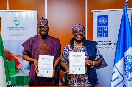 Two officials holding signed documents, standing between UNDP and Nigerian flags.