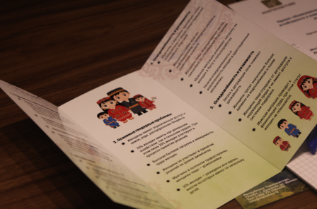 A tri-fold brochure with colorful illustrations and text on a wooden table.