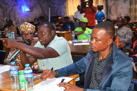 A group of people in a meeting, with one man speaking and others listening attentively.