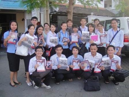 Group of students posing together, holding books, outside a building.