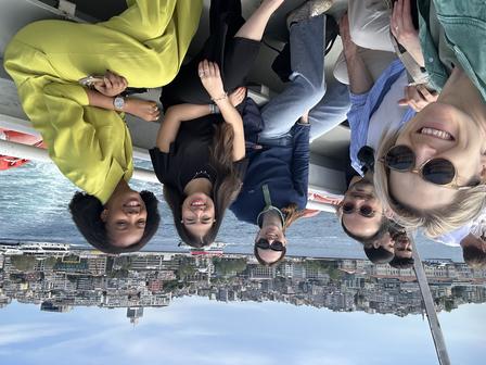 Smiling group of friends posing on a rooftop with the city skyline in the background.