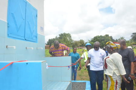 Group of people at an outdoor ribbon-cutting in front of a bright blue building.