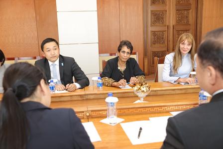 Business meeting around a wooden conference table with several participants.