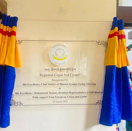 Plaque unveiling for the Regional Legal Aid Center, draped with colorful fabric.