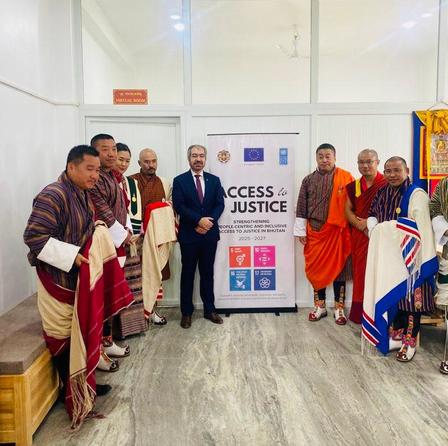 A group of people in traditional attire standing beside a banner that reads "ACCESS to JUSTICE."