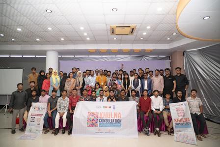 Group photo of a diverse crowd on a stage with banners at the front.