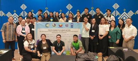 Group of people posing for a photo at a conference, blue geometric backdrop and banner with logos.
