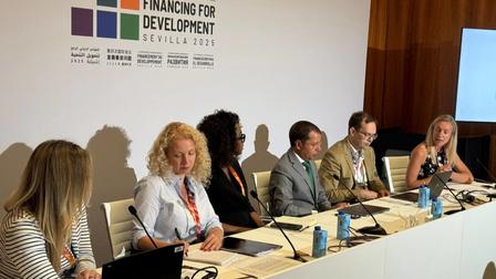 Six panelists at a financing for development conference, seated at a long table.