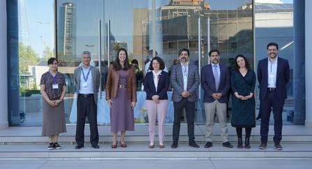 Photograph: Group of professionals in business attire posing outside a glass-front building.