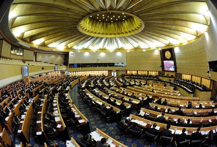 Parliament chamber filled with attendees in curved seating, gold circular ceiling.
