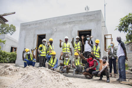 Group of workers on a construction site, in front of a concrete building.