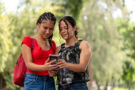 Mujeres jóvenes manipulando teléfono celular