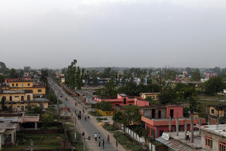 Aerial photograph of a small town street with colorful buildings and trees under a cloudy sky.