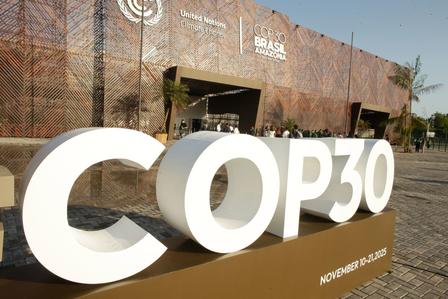 Large white COP30 letters sculpture in front of a conference venue.