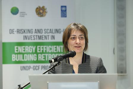 Photo of a speaker at a podium during a conference on energy-efficient building retrofits.