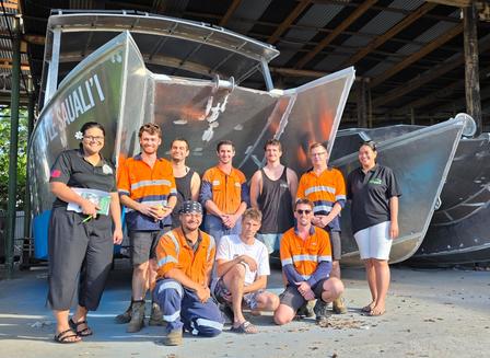 Group photo of volunteers in orange vests posing on an outdoor stage setup.