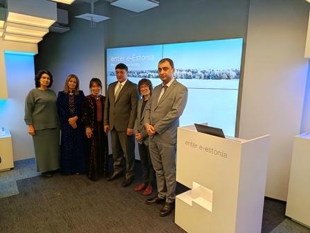 Group of professionals posing in a modern conference room with a cityscape displayed on the screen.