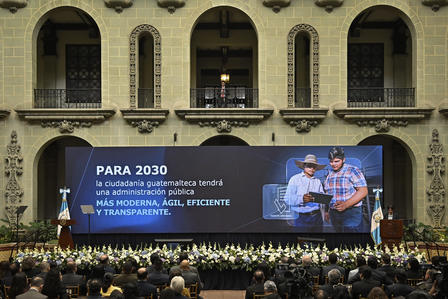 Stage in a grand hall with arches; large PARA 2030 banner and an audience watching.