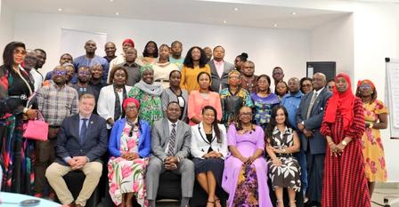 Group of diverse people posing for a photograph in a bright conference room.